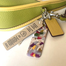 Load image into Gallery viewer, Colorful keychain with a tag attached to a green bag