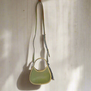 Green leather handbag with a strap on a white background