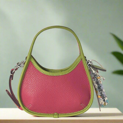 Pink handbag with green handle and trim on a white background