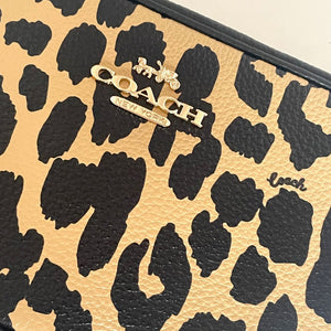 Leopard print clutch with Coach logo on a beige background