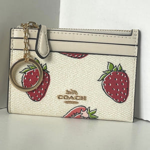Coach cardholder with strawberry pattern and keychain on a neutral background