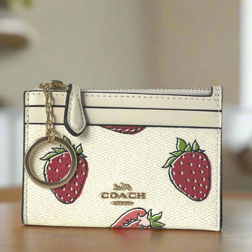 Coach cardholder with strawberry design and keychain on a neutral background