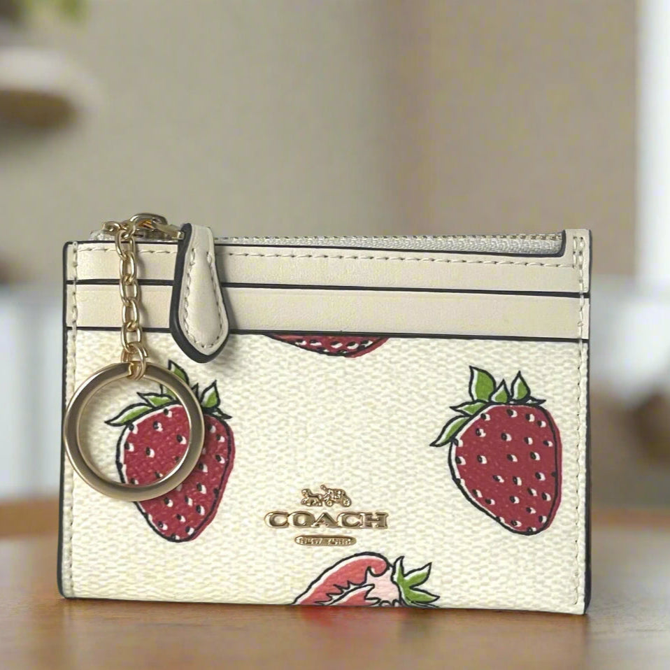 Coach cardholder with strawberry design and keychain on a neutral background