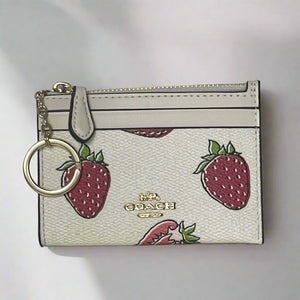 Coach cardholder with strawberry pattern and keychain on a light gray background