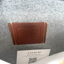 Load image into Gallery viewer, Brown leather cardholder with 'Coach' branding on a textured gray surface.