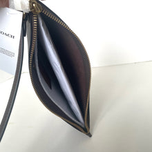 Load image into Gallery viewer, Open black wallet with gold zipper on a white surface, Coach paper in the background