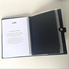 Load image into Gallery viewer, Open notebook with a black cover and white pages on a light background