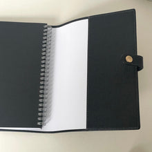 Load image into Gallery viewer, Black spiral-bound notebook with a white interior on a beige background