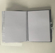 Load image into Gallery viewer, Open spiral-bound notebook with lined pages on a light gray background
