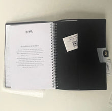 Load image into Gallery viewer, Black spiral-bound notebook with a white label on a light gray background