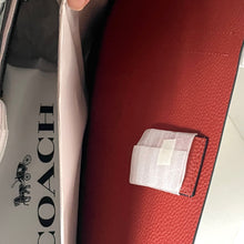 Load image into Gallery viewer, Red leather bag with a patch and a Coach branded box in the background