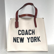 Load image into Gallery viewer, Beige tote bag with 'Coach New York' text and brown leather handles on a white background