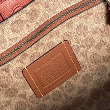 Load image into Gallery viewer, Close-up of a Coach bag with a brown leather label and zipper.