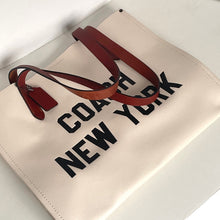 Load image into Gallery viewer, Beige tote bag with 'Coach New York' text and brown leather strap on a light gray background
