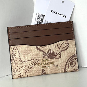 Coach cardholder with brown leather strip and logo on a light gray background