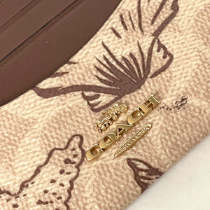 Close-up of a Coach wallet with gold hardware on a patterned background