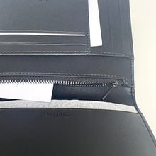 Load image into Gallery viewer, Black leather passport holder with zipper on a light beige background