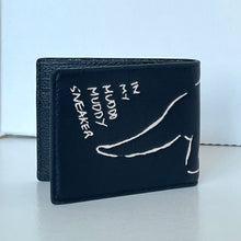 Load image into Gallery viewer, Black wallet with white text and foot illustration on a light background