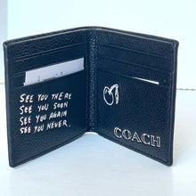 Load image into Gallery viewer, Open black leather wallet with text and Coach logo on a white background