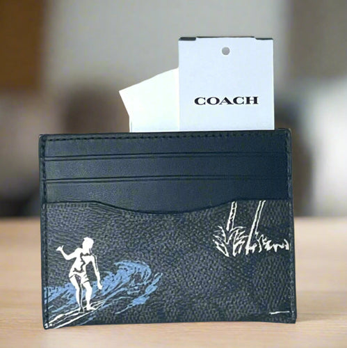 Black cardholder with white and blue designs on a white background, featuring a Coach tag.