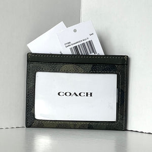 Black Coach cardholder with a white card inside on a light gray background
