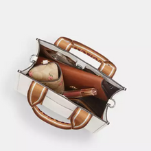 Load image into Gallery viewer, Brown handbag with a white interior on a light gray background