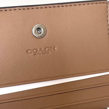 Load image into Gallery viewer, Close-up of a brown Coach wallet with a visible logo.