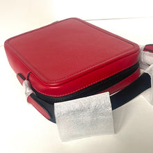 Load image into Gallery viewer, Red leather case with a black strap and silver tag on a white background