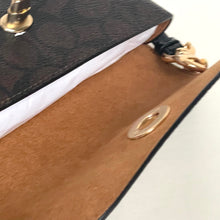 Load image into Gallery viewer, Close-up of a handbag with brown leather flap and gold hardware.