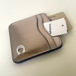 Brown leather cardholder with a tag on a light beige background