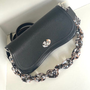 Black leather handbag with a patterned chain strap on a white background