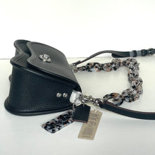 Load image into Gallery viewer, Black leather dog muzzle with a patterned leash and tag on a white background