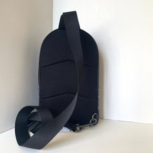 Black sling bag with a textured back on a white background