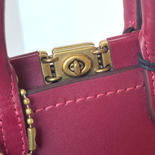 Load image into Gallery viewer, Close-up of a pink handbag with a gold lock detail