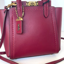 Load image into Gallery viewer, Pink handbag with gold clasp and brand tag on a white background