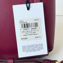 Load image into Gallery viewer, Maroon handbag with a white tag displaying product details and barcode.