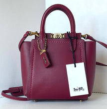 Load image into Gallery viewer, Maroon handbag with gold accents and a visible brand tag on a white background