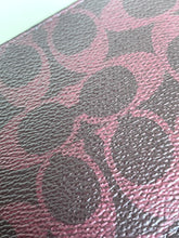 Load image into Gallery viewer, Close-up of a textured leather surface featuring the signature Coach 'C' monogram pattern in metallic pink over a dark brown base.