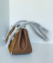 Load image into Gallery viewer, A brown leather handbag with a textured cowhide side panel, wrapped in protective plastic packaging, set against a plain white background.