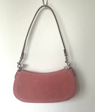 Load image into Gallery viewer, A dusty rose pink suede shoulder bag with a thin brown leather strap and silver-tone hardware, hanging from a metal hook against a plain off-white wall.