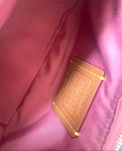 Load image into Gallery viewer, Close-up of the interior lining of a pink or mauve nylon bag, showing a tan leather brand patch with gold-tone stitching and a zipper pull at the edge.