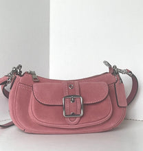 Load image into Gallery viewer, A dusty pink suede crescent-shaped shoulder bag with a silver-tone buckle on the front flap and a matching leather tag, shown against a plain white background.