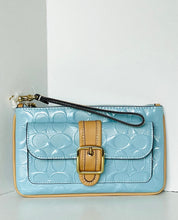 Load image into Gallery viewer, A light blue embossed leather wristlet clutch with a tan leather strap and gold-tone buckle closure, shown against a plain white background.