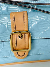 Load image into Gallery viewer, Close-up of a light blue embossed leather handbag with a tan leather strap and a shiny gold buckle closure.