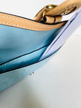 Load image into Gallery viewer, Close-up of a light blue textured handbag with tan leather trim and gold-tone hardware, showing the interior lining and a white paper insert.
