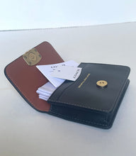 Load image into Gallery viewer, An open Coach wallet in two-tone brown and black leather with gold-tone hardware, shown on a plain light background with a branded card and paper tag visible inside.