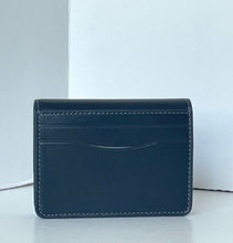 Load image into Gallery viewer, A dark navy blue leather card holder wallet with white contrast stitching, standing upright on a light gray surface against a white background.