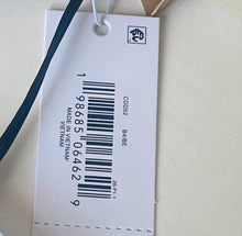 Load image into Gallery viewer, A white paper retail price tag with a barcode, product code CDD02, size B/GE, and text including 'MADE IN VIETNAM' and 'MFSRP $75.00 USD', photographed on a light beige surface.