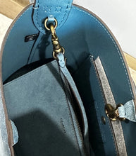 Load image into Gallery viewer, Close-up of the interior of a blue leather handbag, showing a matching zip-around pouch, interior pockets, gold-tone hardware, and stitching.