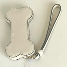 Load image into Gallery viewer, Beige bone-shaped pouch with a strap on a light beige background